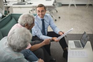 Professional financial advisors discussing investment strategies with clients around conference table