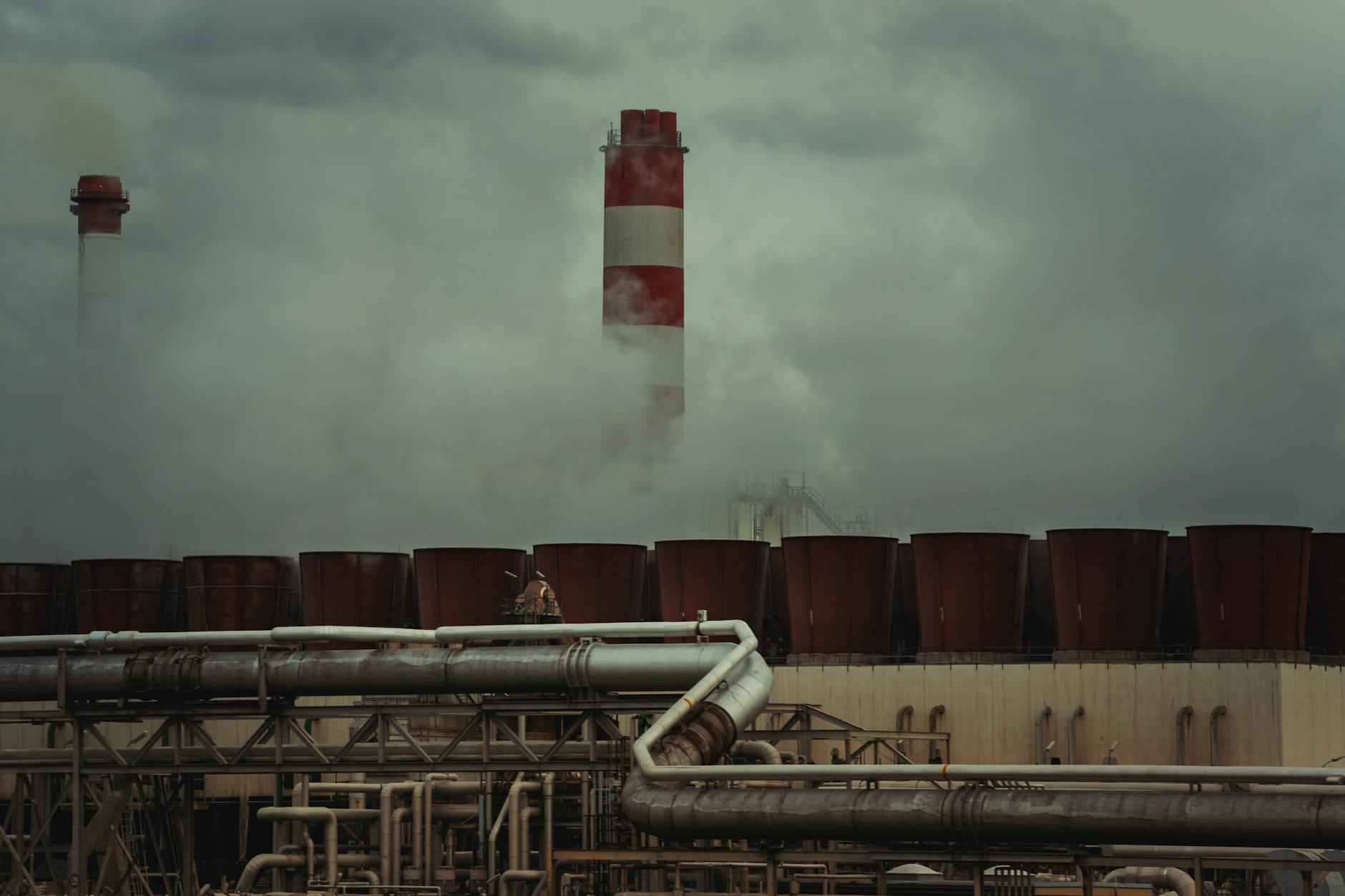 Industrial manufacturing facility with smokestacks against cloudy sky