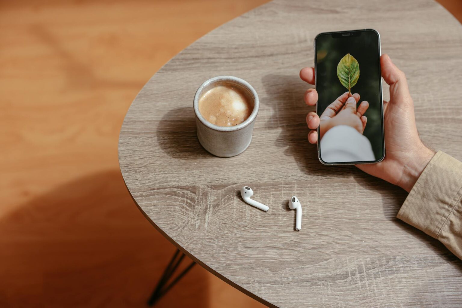 Person using smartphone while holding coffee cup, representing mobile app usage in coffee shops