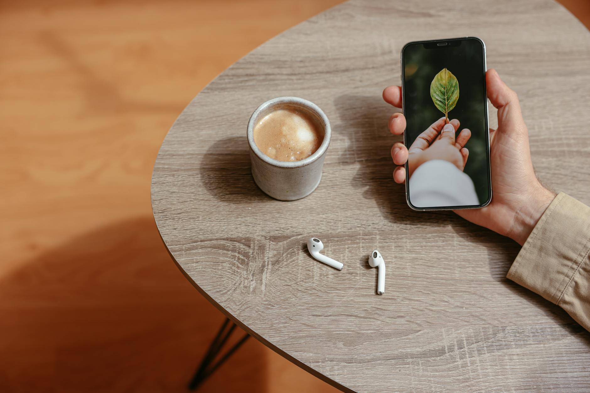 Person using smartphone while holding coffee cup, representing mobile app usage in coffee shops