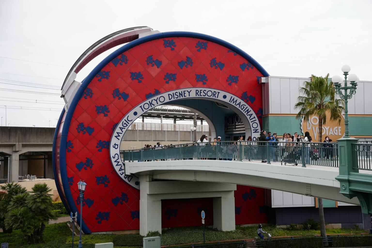 Large crowds of visitors walking through a busy theme park with attractions visible in the background
