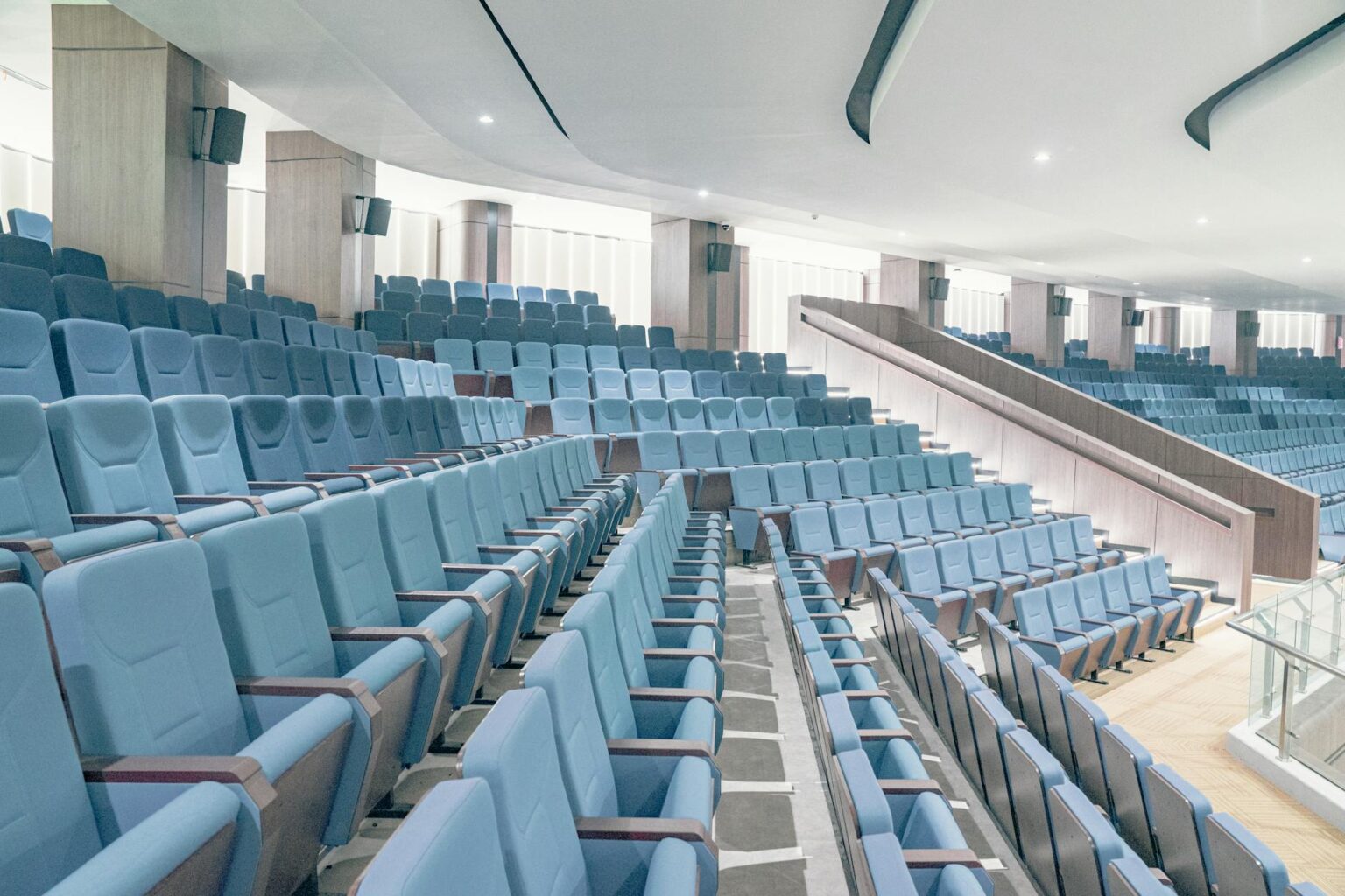 Empty movie theater auditorium with rows of red seats and large screen