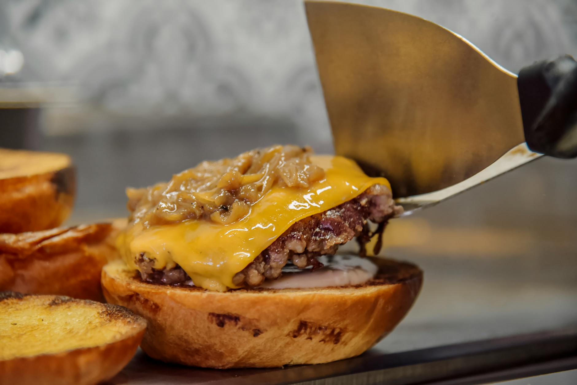 Commercial kitchen worker preparing burgers on industrial grill in fast food restaurant