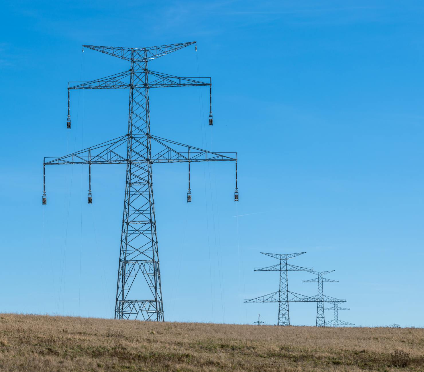 High voltage electrical transmission towers and power lines against cloudy sky