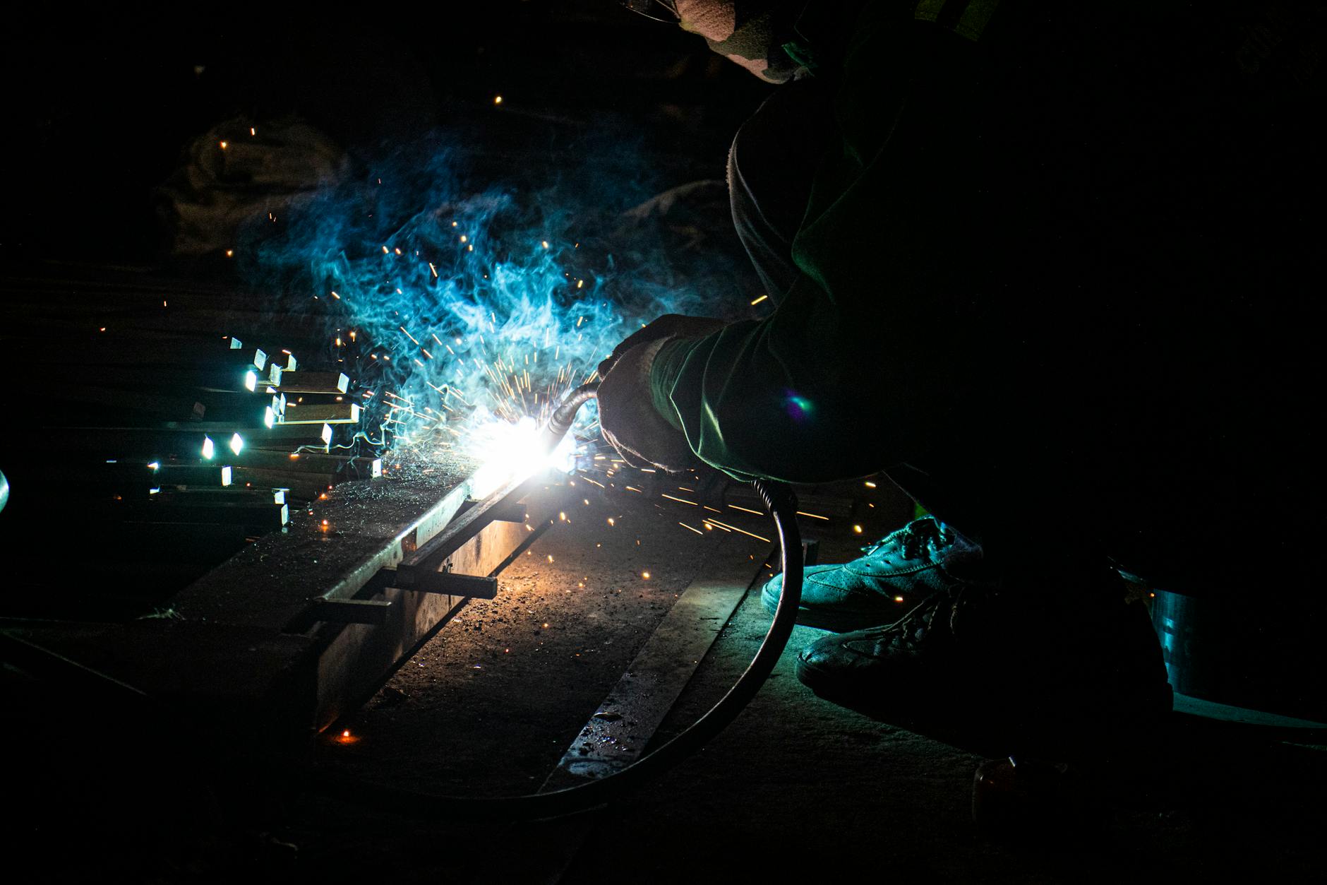 Skilled welder creating bright sparks while working on metal fabrication