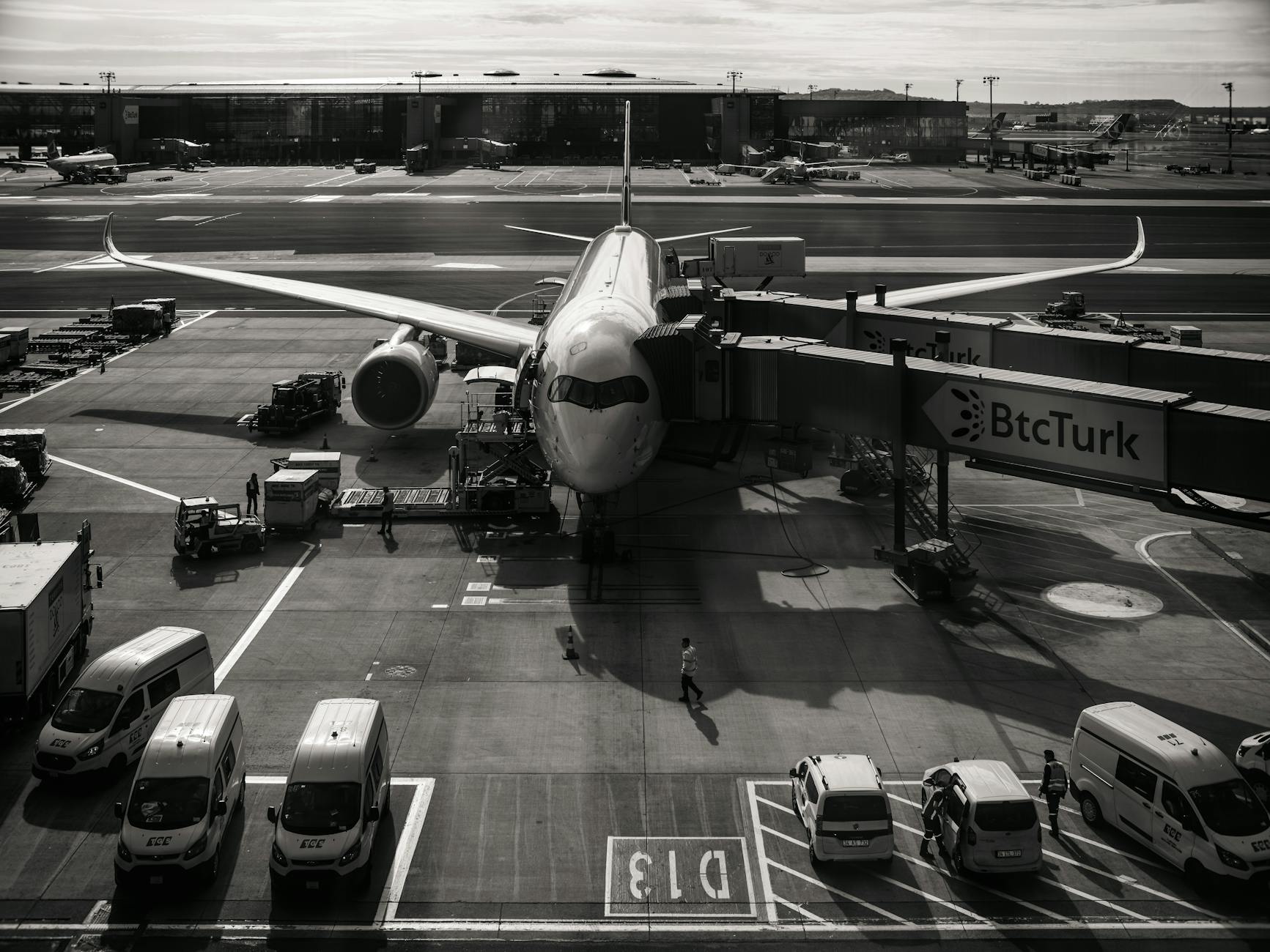 Commercial aircraft on airport runway prepared for departure with cargo loading operations in background