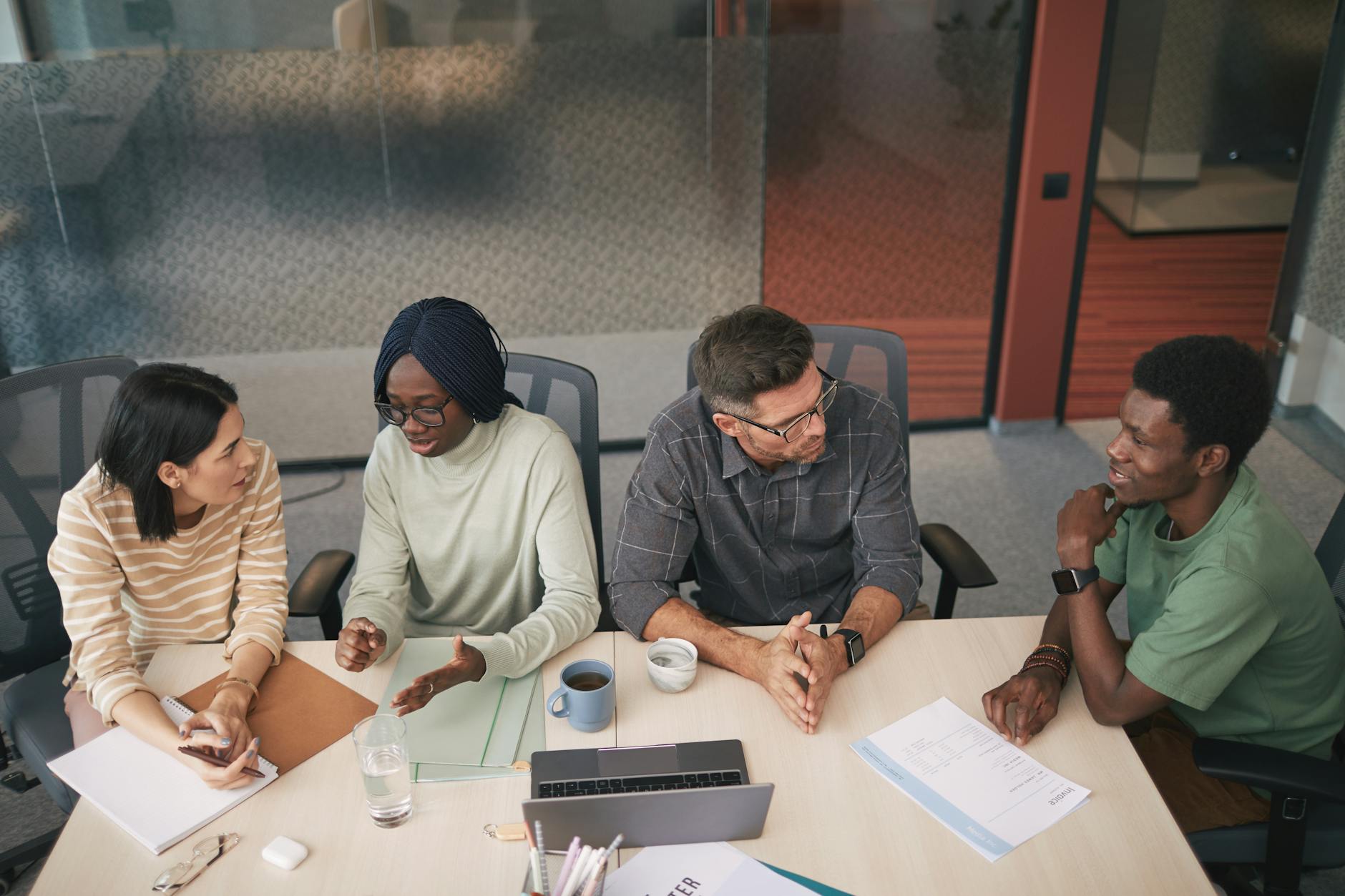 Diverse business team having productive discussion around conference table in bright office space