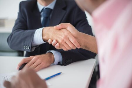 Business professionals shaking hands over financial documents