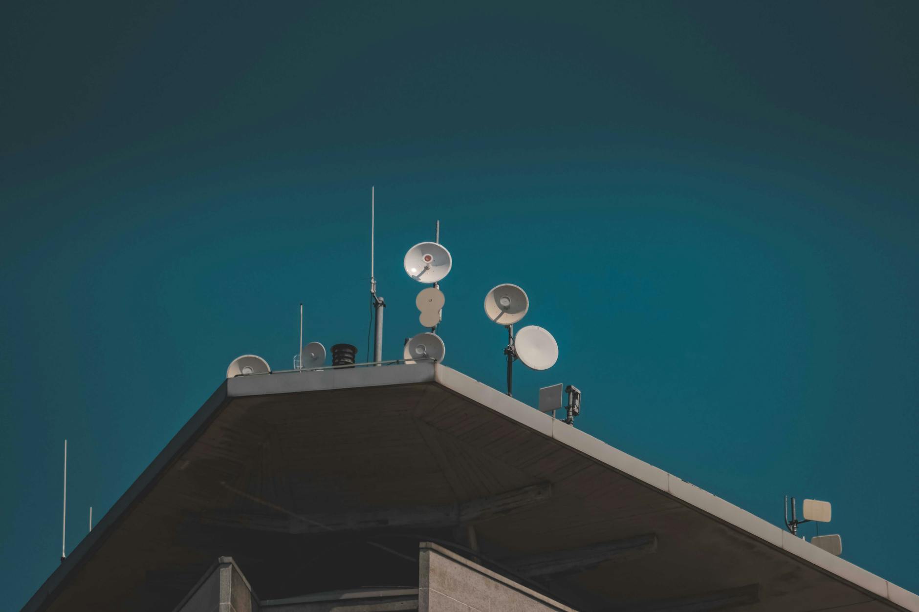 Military satellite communication dish against a cloudy sky