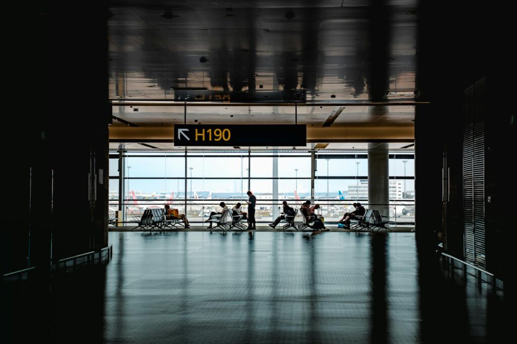 Travel Stocks Surge on Iran Ceasefire Hopes, But Not Everyone Is Buying It Travelers walking through a busy airport terminal during peak travel season