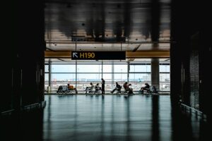 Travel Stocks Surge on Iran Ceasefire Hopes, But Not Everyone Is Buying It Travelers walking through a busy airport terminal during peak travel season