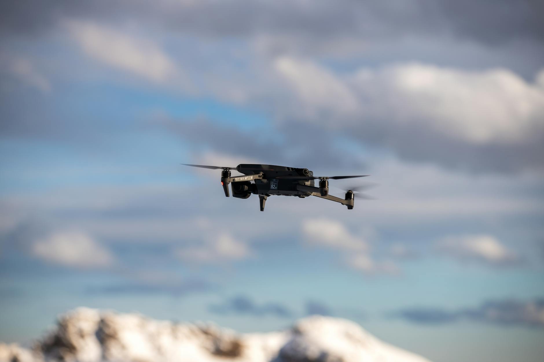 Military drone in flight over open terrain
