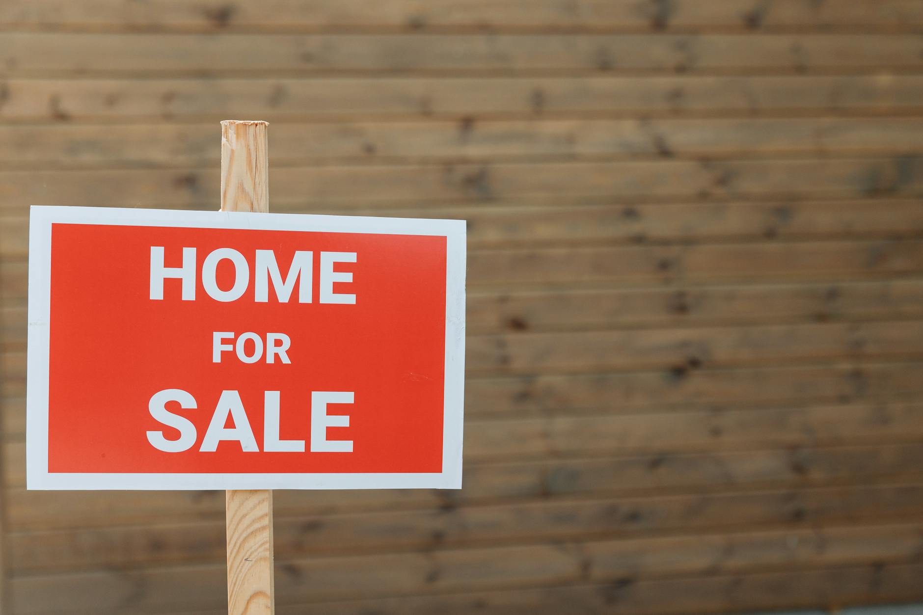 A for-sale sign in front of a residential property representing the California housing market