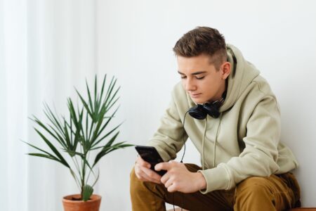 Starmer Moves to Ban Young Teens From Social Media Young teenager scrolling on a smartphone in a dimly lit room