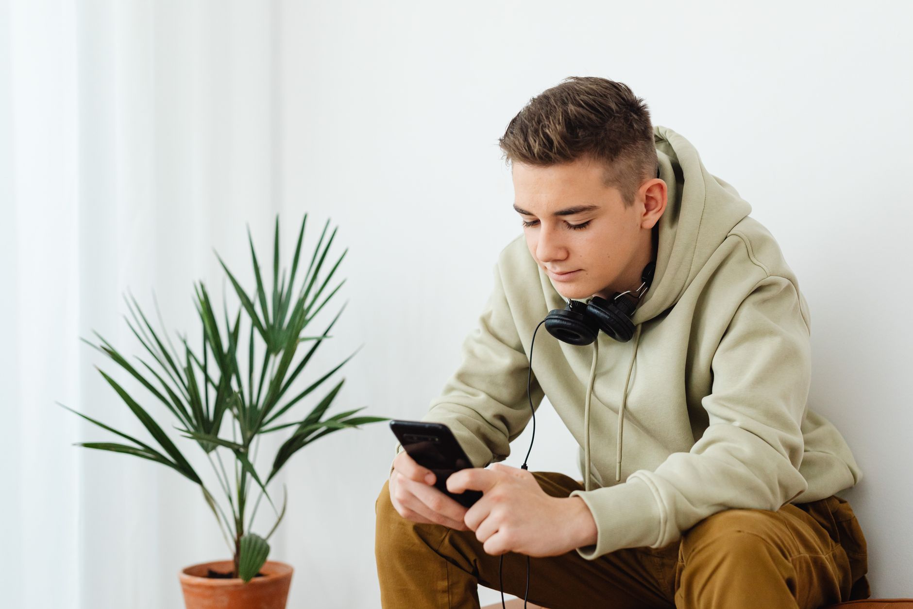 Young teenager scrolling on a smartphone in a dimly lit room