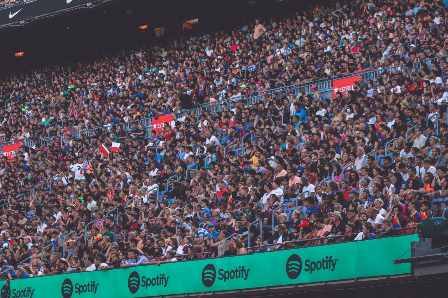 Fans gathered outside a large sports stadium holding tickets and phones