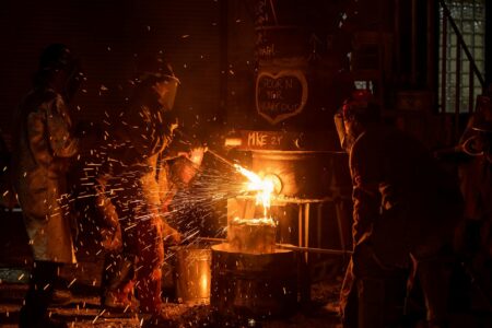 Workers on a metal foundry production floor in industrial setting