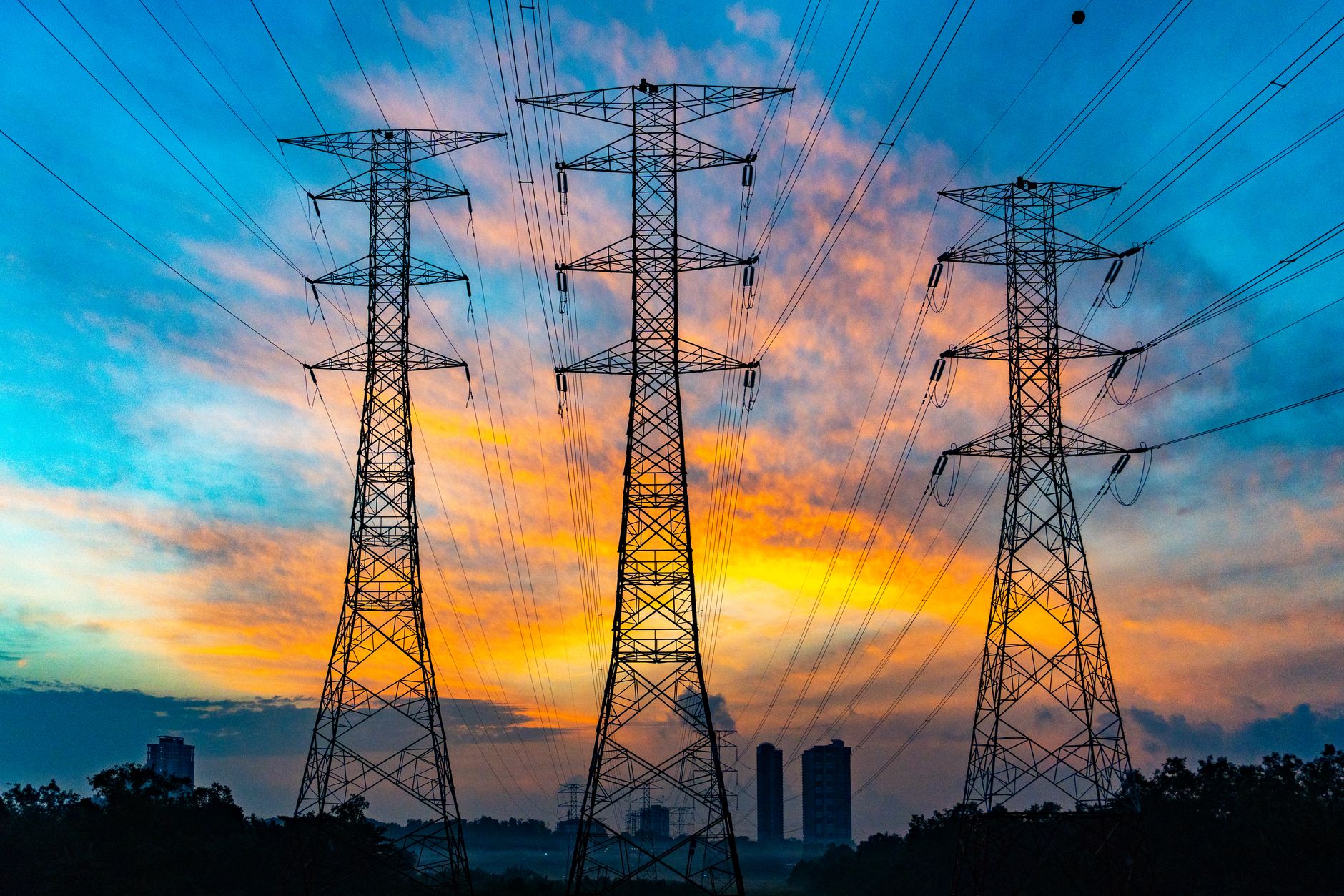 High-voltage power transmission lines and electrical grid infrastructure at dusk