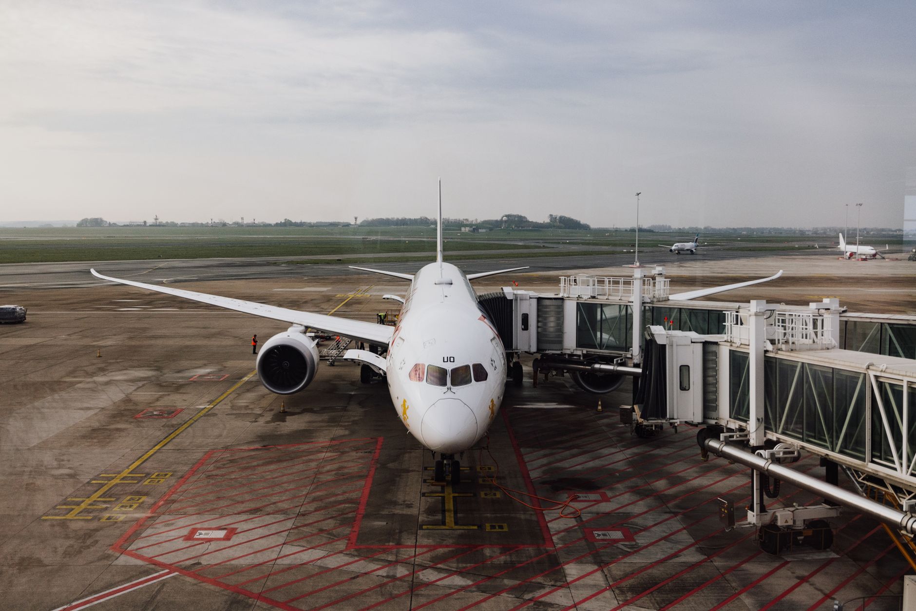 Busy international airport terminal with aircraft visible through windows