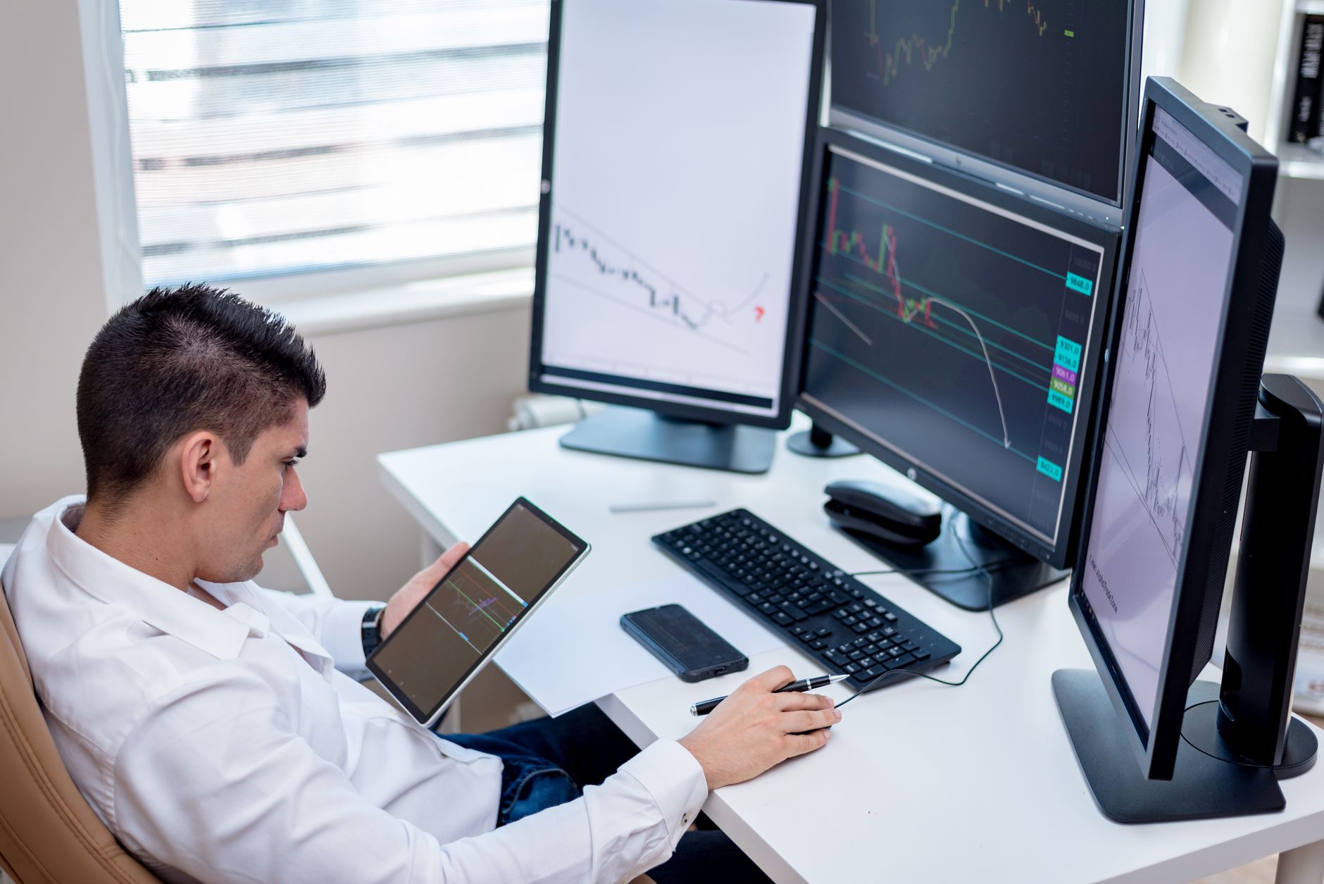Financial trader watching multiple monitors displaying market data during a volatile session