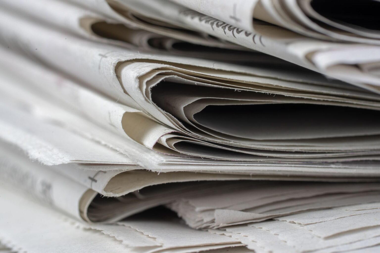 Close-up of a newspaper printing press rolling out fresh pages