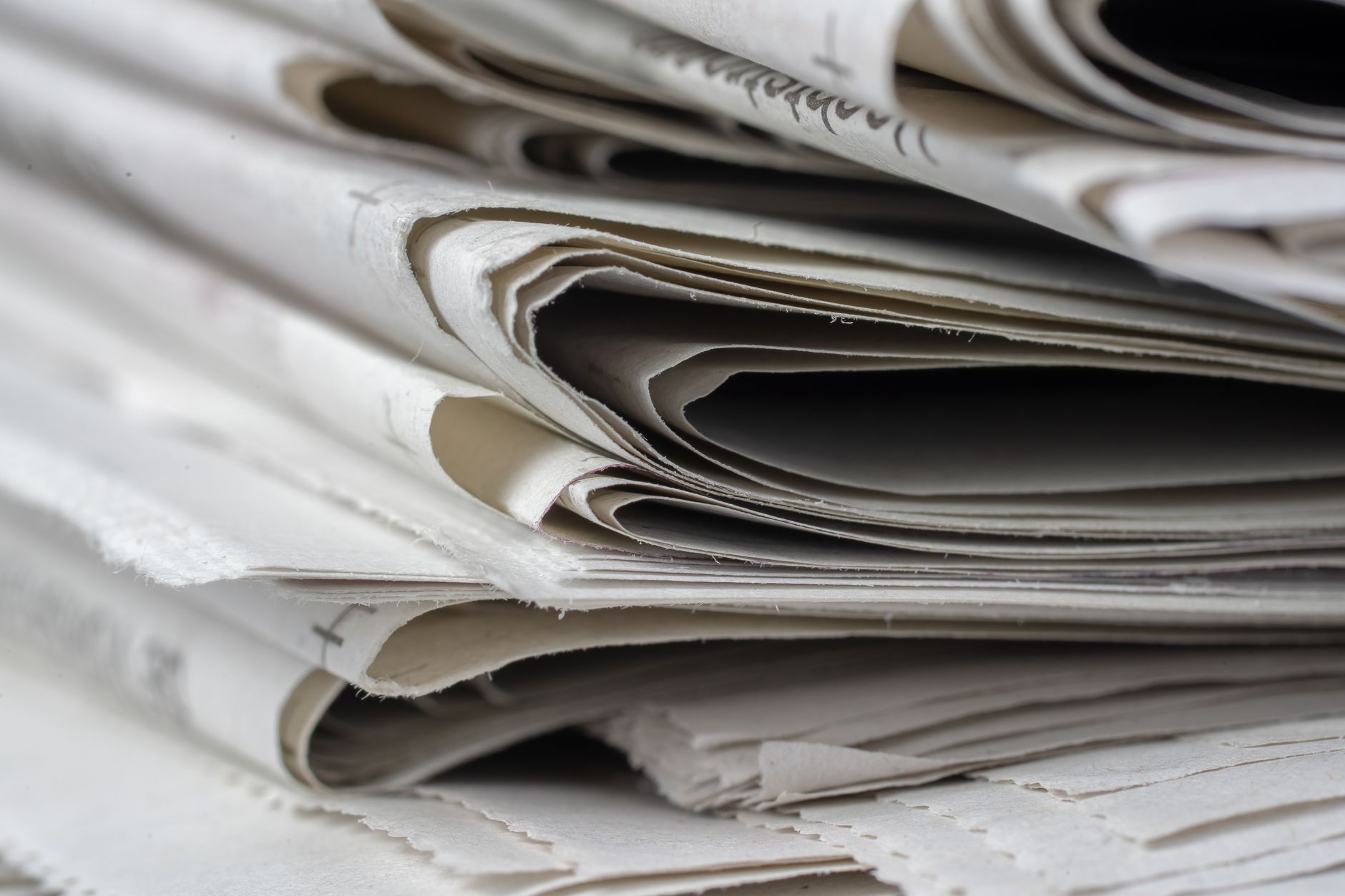 Close-up of a newspaper printing press rolling out fresh pages