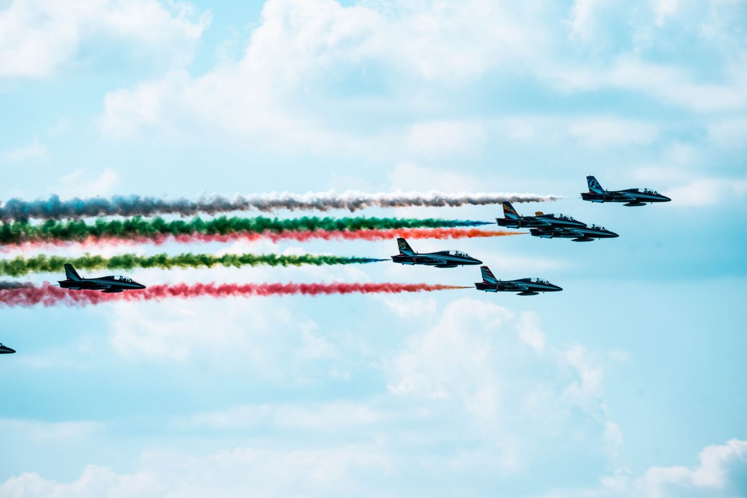 Military aircraft flying over conflict zone with smoke rising below