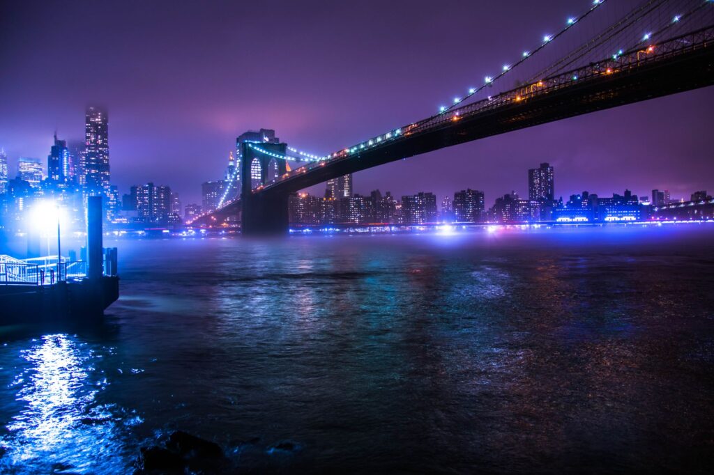 Brooklyn Bridge illuminated at night with city skyline in the background