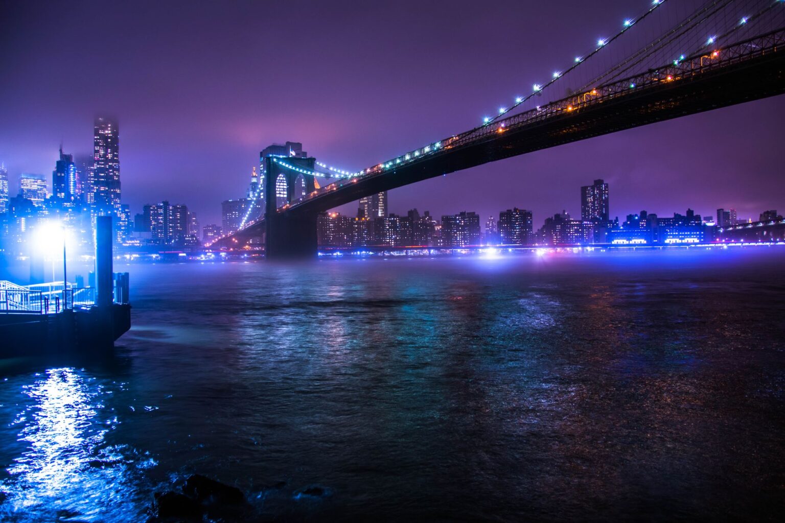 Brooklyn Bridge illuminated at night with city skyline in the background