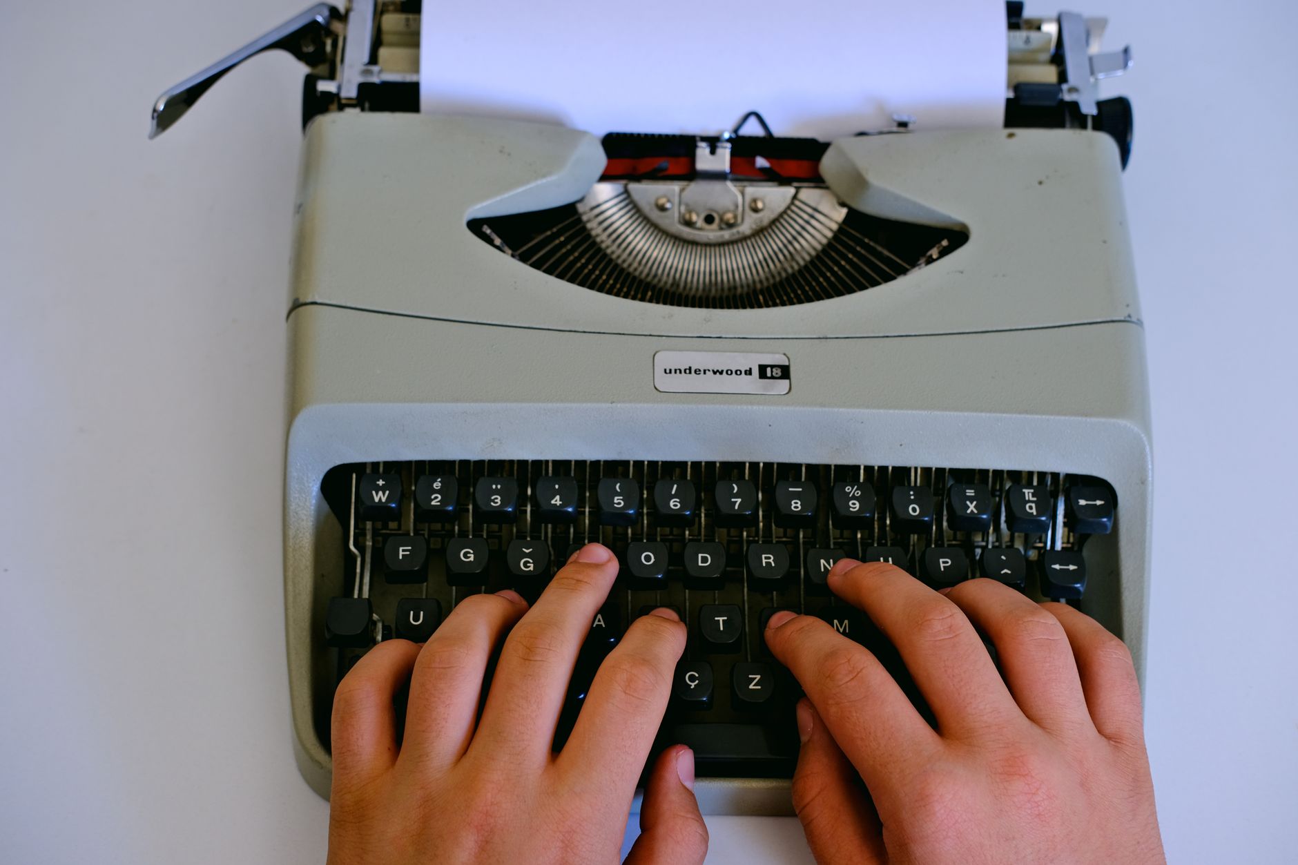 A journalist typing on a laptop in a newsroom setting