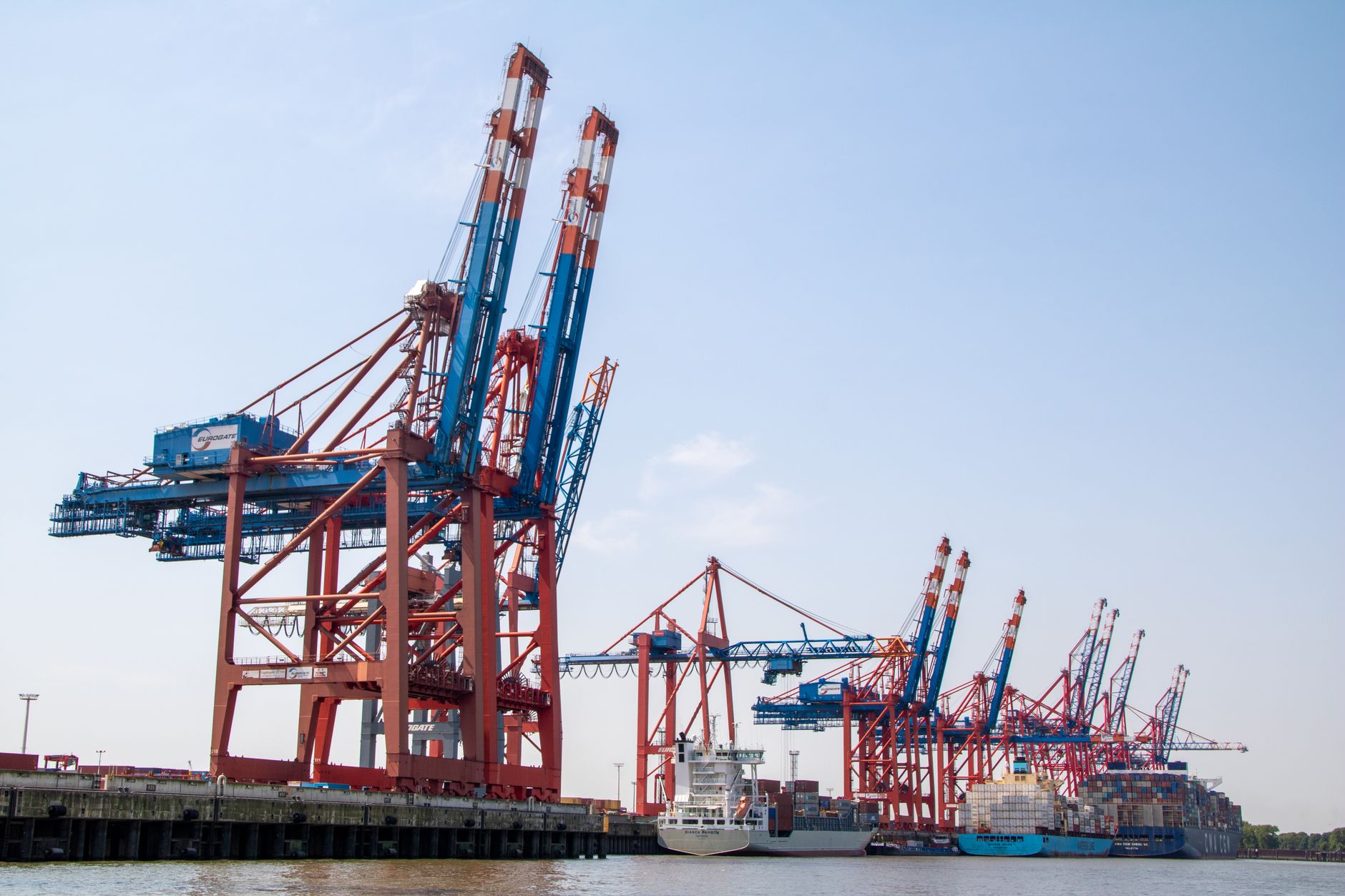 Aerial view of industrial port terminal with cargo ships docked at berths