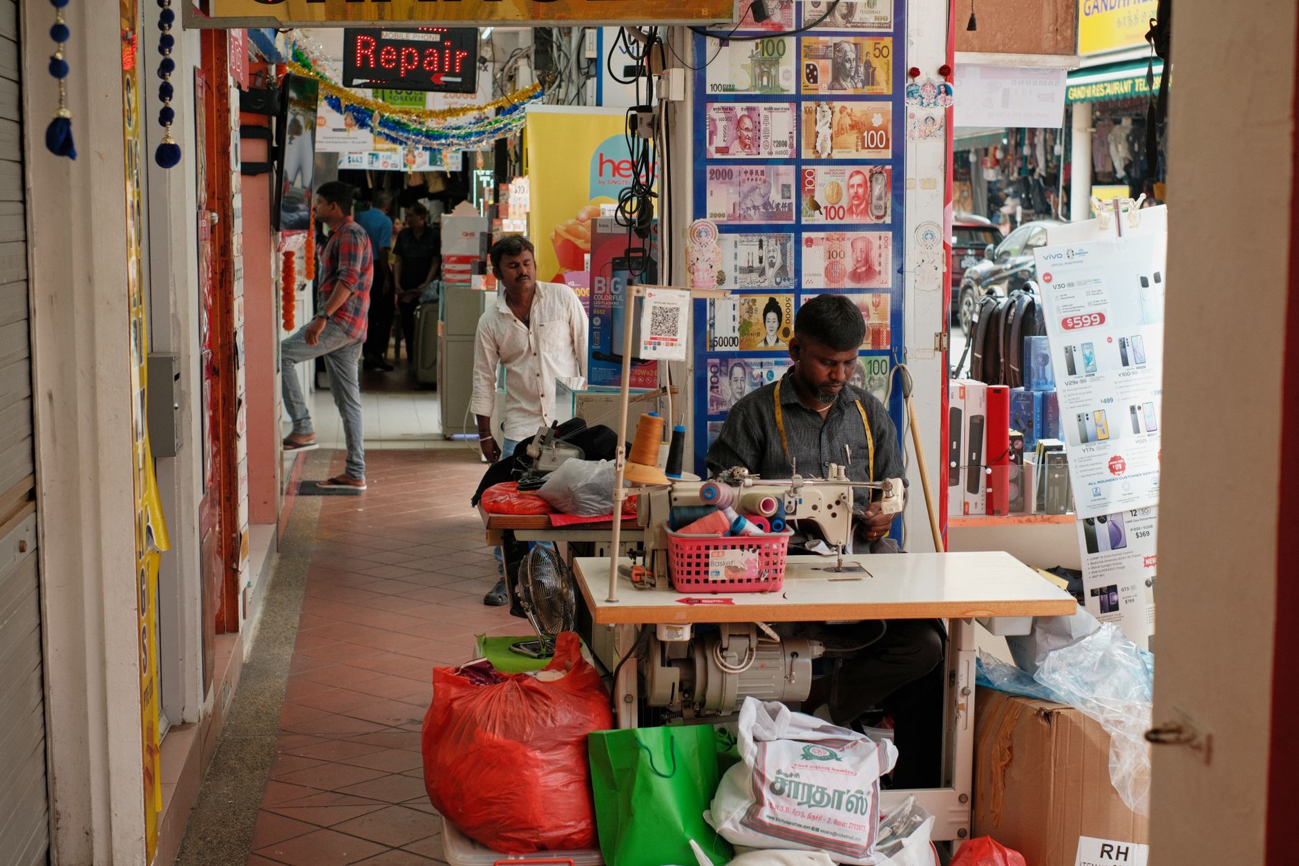 A tailor repairing a jacket inside a clothing store