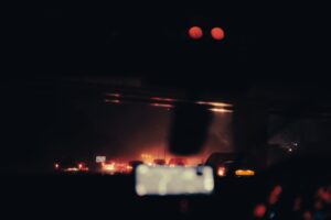 Bright car headlights illuminating a dark road at night
