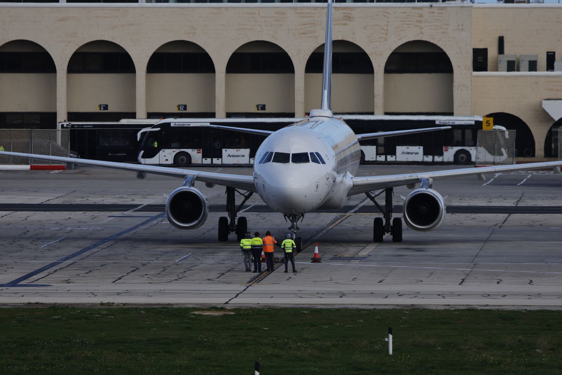Ground crew working near a large cargo aircraft at a busy airport