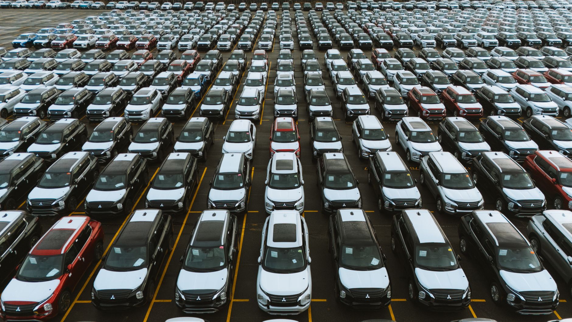 Row of new vehicles on a car dealership lot under bright lighting